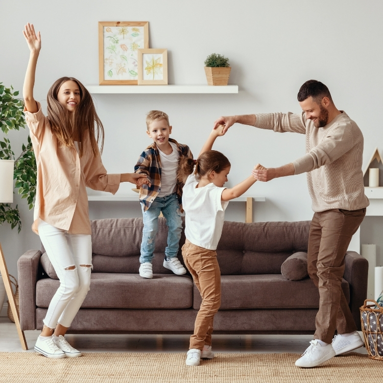 Parents dancing around the living room with their young children